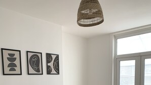 Un comedor moderno con una mesa de madera, caminos de mesa negros y un corredor tejido. Tres obras de arte enmarcadas decoran la pared.