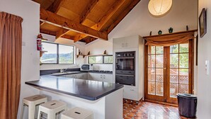 Una cocina con una isla grande, dos taburetes de bar, un microondas, un horno y un ventanal con vistas panorámicas.