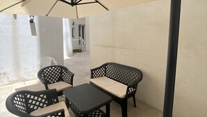 Uma área externa com mesas e cadeiras, um grande guarda-sol e um poste de metal.
