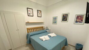Quarto com cama, mesa de cabeceira, guarda-roupa e obras de arte nas paredes.