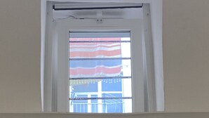 Quarto com janela para uma varanda com toldo listrado.