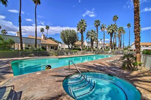 A swimming pool with a diving board, surrounded by palm trees and houses. - Tennis, Golf & Pools: Lovely Palm Desert Condo! (Palm Desert)