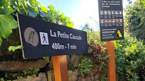 En skylt som visar vägen till La Petite Cascade och anger att det är en vandring på 400 meter som tar cirka 7 minuter.