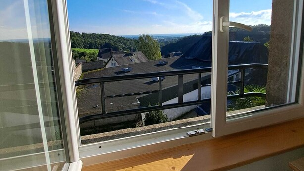 En utsikt från en balkong med en klar himmel, ett avlägset landskap och en byggnad med ett platt tak.