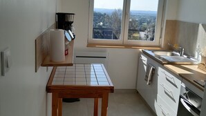 Ett modernt kök med ett stort fönster, en kaffemaskin och ett träbord.