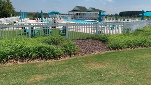 A pool area with a white fence, lounge chairs, and umbrellas. - Beautiful Lakeside Condo/The Maples Golf Course On Site/Golf Haven/Near Pinehurst & Southern Pines/40 Golf courses minutes awaySleeps 9 (Vass)