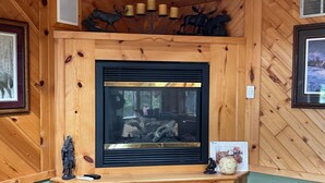 A wooden cabin interior with a fireplace, framed pictures, and wooden wall decor. - Four Season Private Retreat (Hager City)