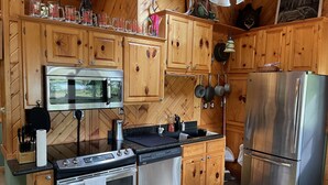A kitchen with wooden cabinets, stainless steel appliances, and a microwave. - Four Season Private Retreat (Hager City)