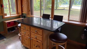 A kitchen with wooden cabinets, a black countertop, and a large window offering a view of the outdoors. - Four Season Private Retreat (Hager City)