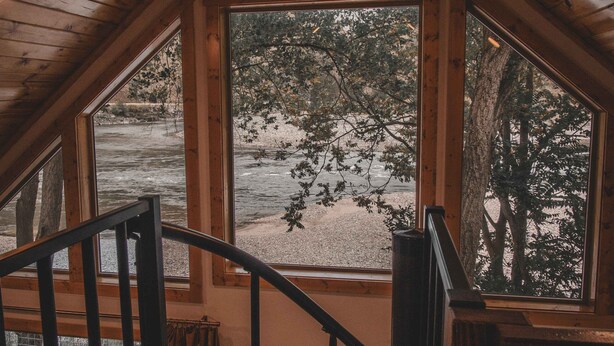 Un intérieur en bois avec un escalier menant à un balcon donnant sur une rivière.