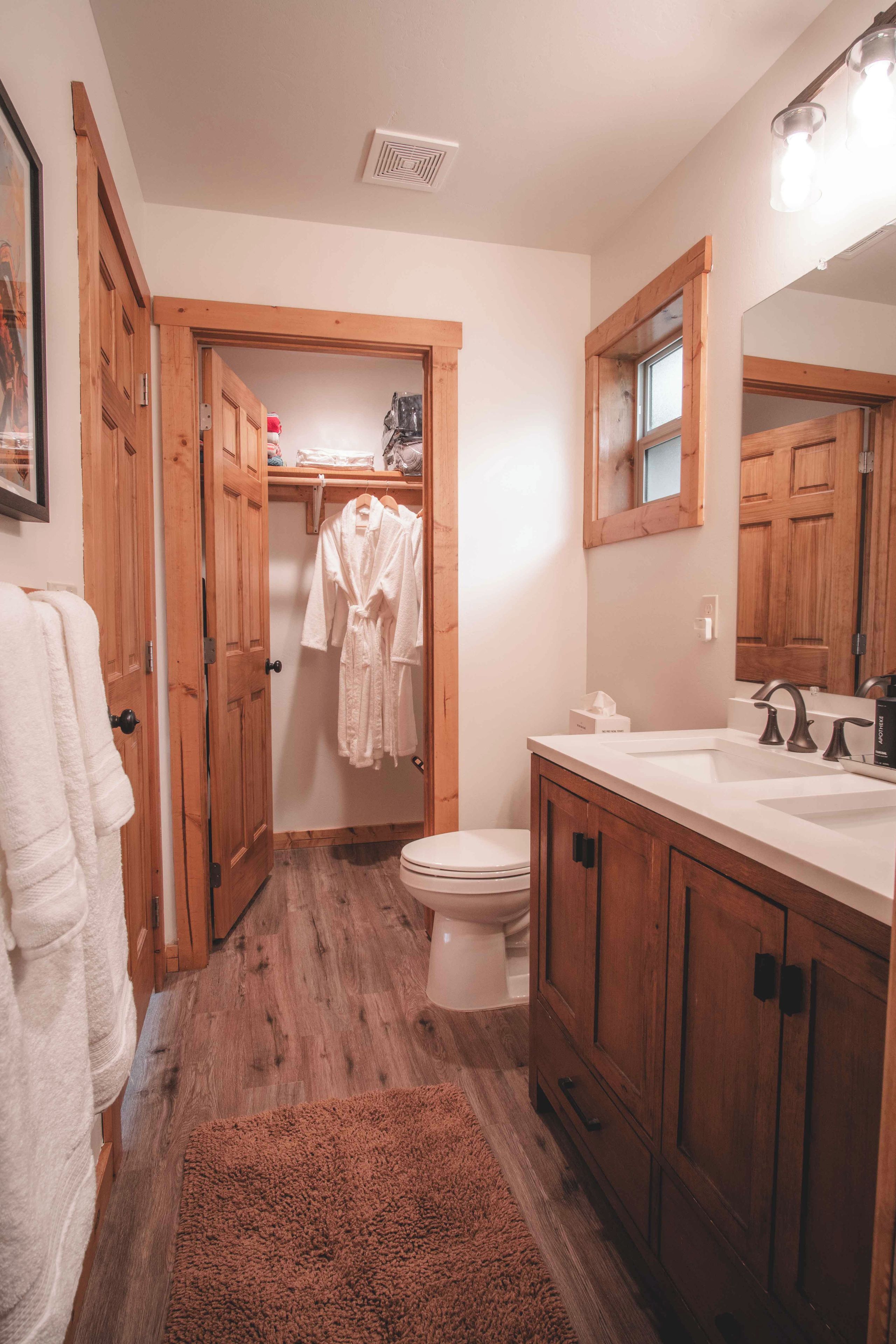 A bathroom with wooden cabinets, a white sink, and a toilet.