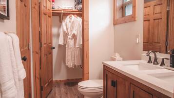 A bathroom with wooden cabinets, a white sink, and a toilet.