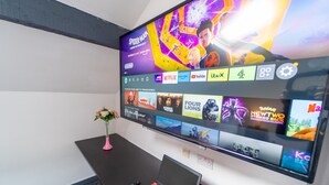 Seinälle asennettu litteänäyttöinen televisio, jossa näkyy erilaisia suoratoistopalveluita ja suosittuja elokuvia.