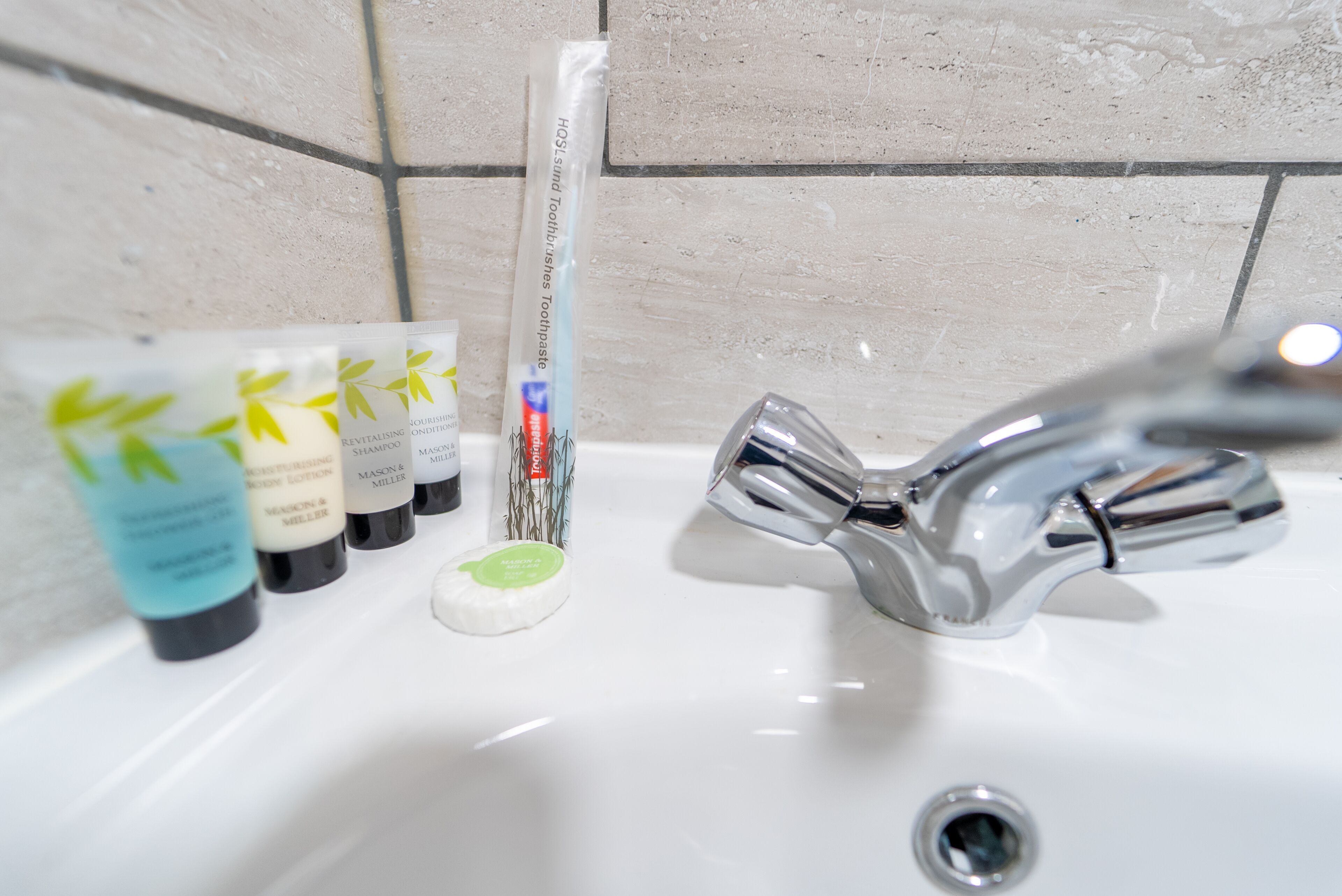 Ein Badezimmerwaschbecken mit Toilettenartikeln, darunter Zahnbürste, Zahnpasta und Seife.