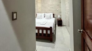 A modern hotel room with a wooden bed, a nightstand, and a wall-mounted air conditioner. - Bellazio Aparthotel (Iquitos)