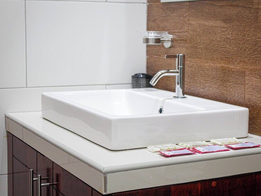 Un baño con un lavamanos blanco, un grifo cromado y una pared de madera.