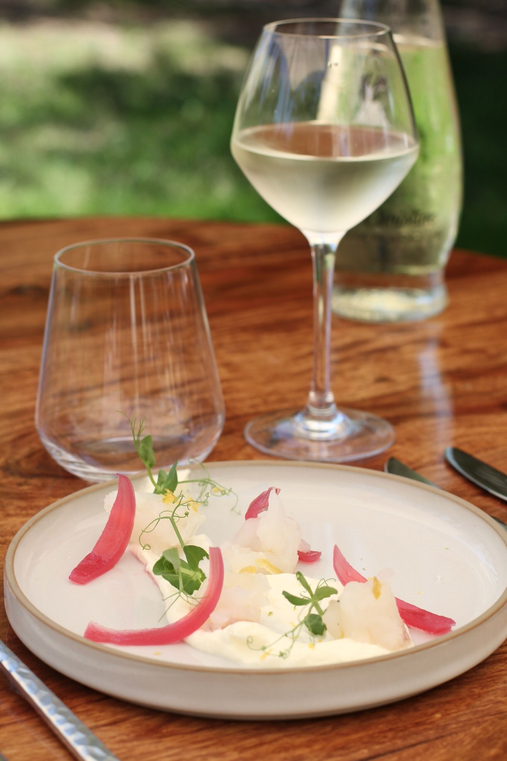 Une table à manger avec une assiette de nourriture, deux verres à vin et un couteau.