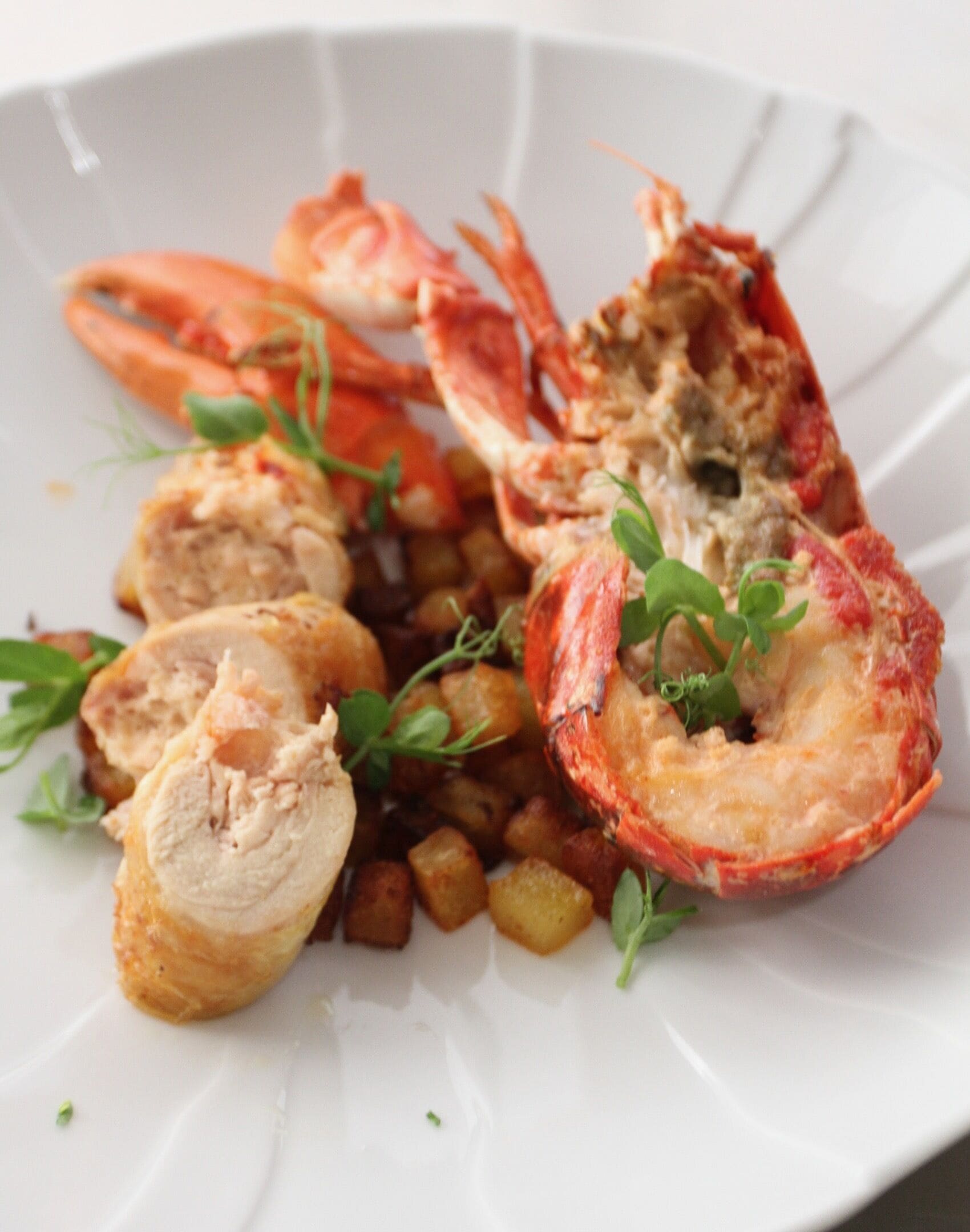 Prato com lagosta cozida, batatas e ervas.