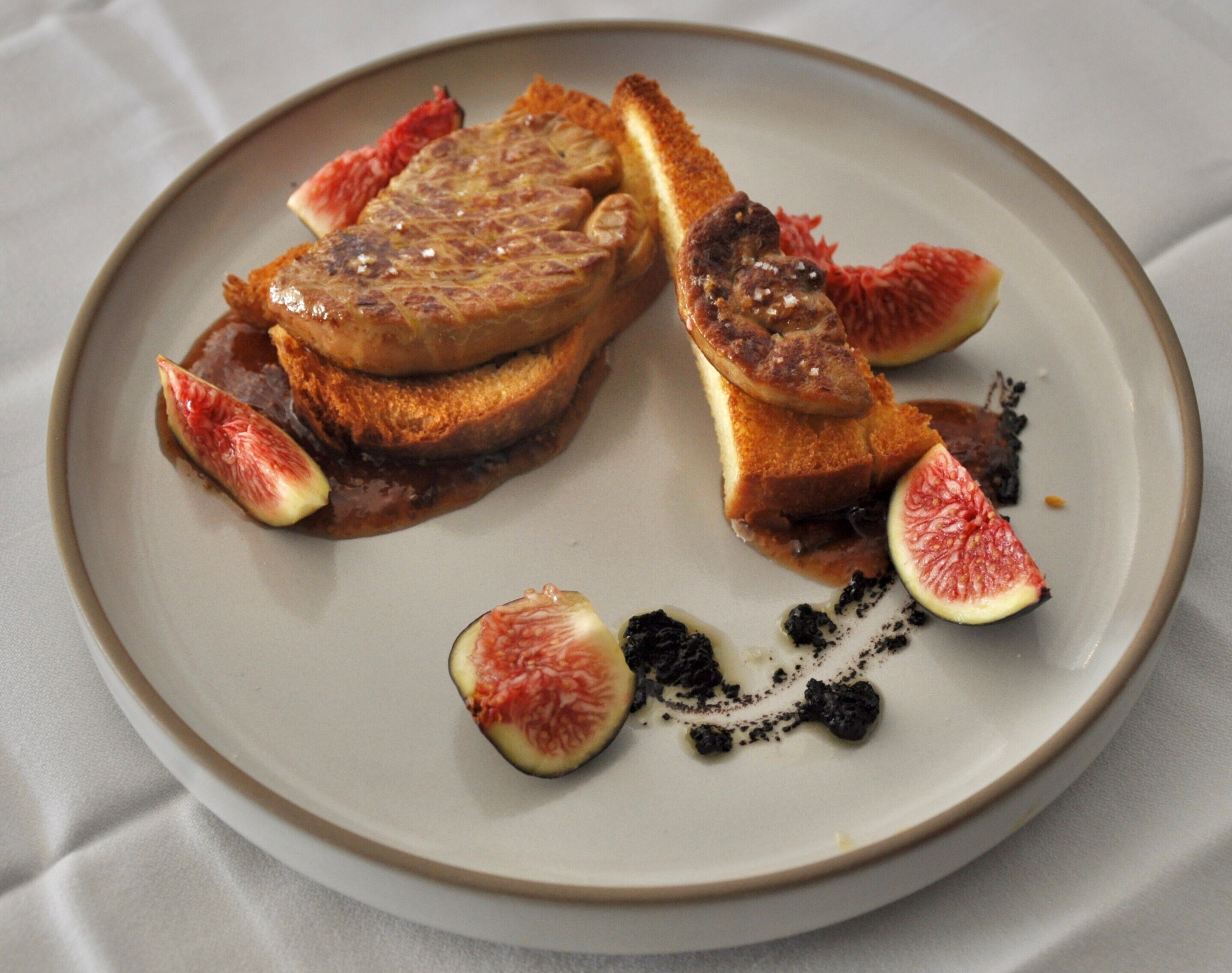A plate with grilled steak, toast, and figs.