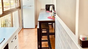 A compact kitchen with a refrigerator, a dining table with chairs, and a window providing natural light. - 59 Tourist House Bologna lame (Bologna)