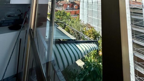 A modern apartment with a large window, a kitchen area, and a view of neighboring buildings. - 59 Tourist House Bologna lame (Bologna)