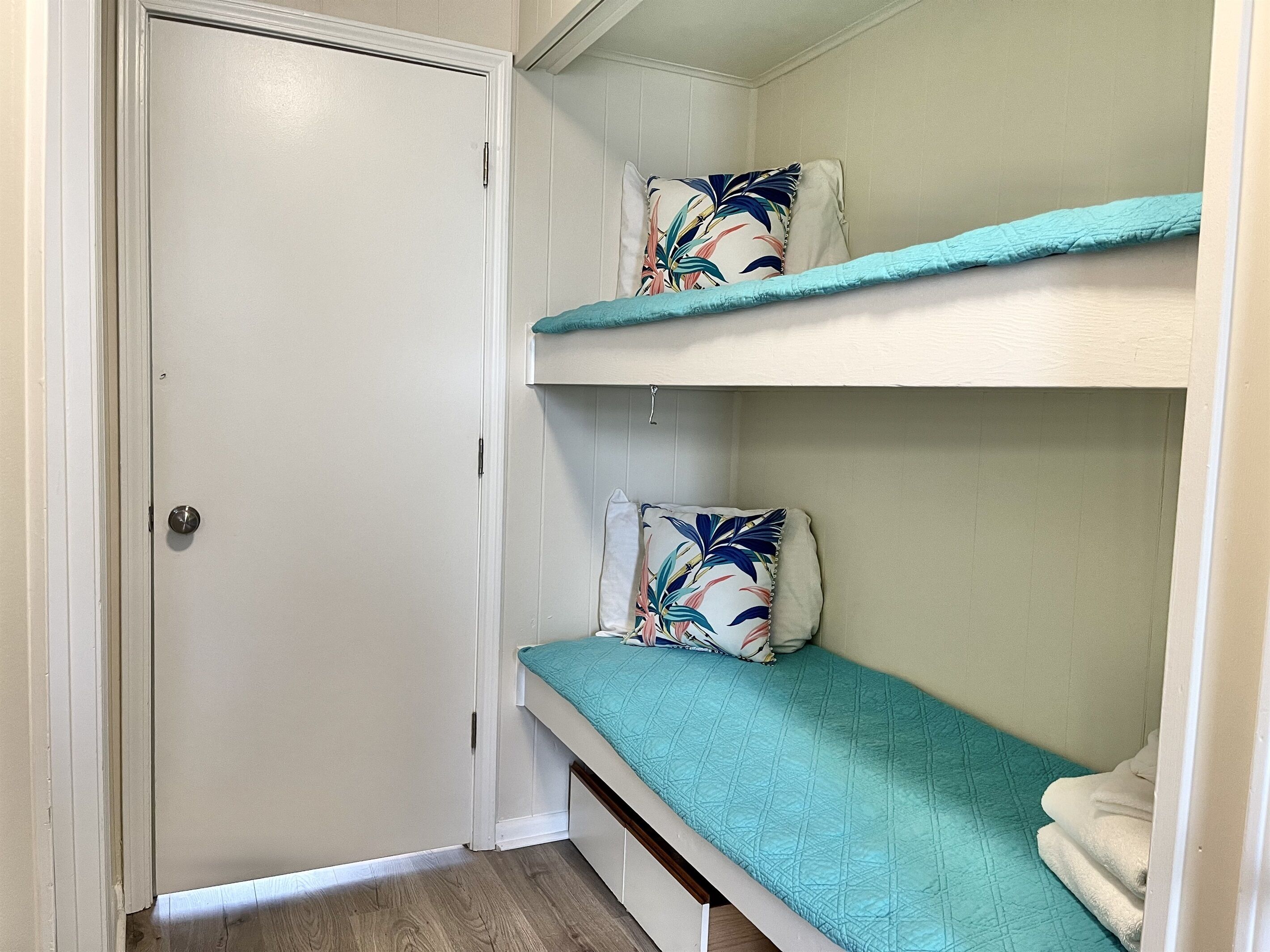 Ein kleiner, kompakter Raum mit einem Etagenbett und einer Tür.