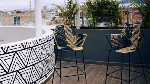 A rooftop terrace with two wicker chairs and a patterned wall. - Estainn Hotel Coworking (Bogotá)