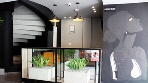 A reception area with a modern staircase, potted plants, and a large wall mural. - Estainn Hotel Coworking (Bogotá)