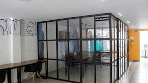 A meeting room with glass walls, a wooden table, and black chairs. - Estainn Hotel Coworking (Bogotá)