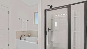 Ein modernes Badezimmer mit einer freistehenden Badewanne, einer gläsernen Dusche und einer weiß gefliesten Wand.