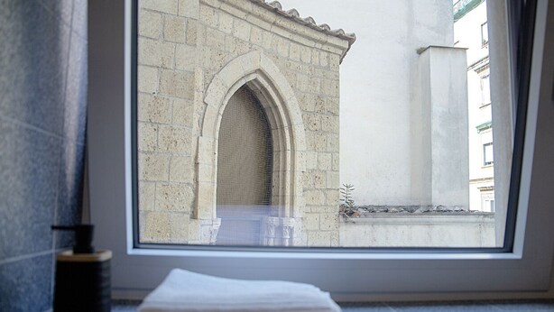Un bany amb finestra que fa vedes a un edifici de pedra amb un arc d'entrada.