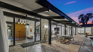 Une terrasse extérieure moderne, dotée d’une structure vitrée, d’un espace salon et d’un foyer.