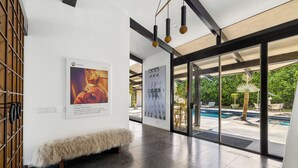Un intérieur moderne avec vue sur la piscine, un banc recouvert de fourrure et des œuvres d’art accrochées aux murs.
