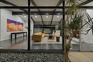 Una sala de estar moderna con pared de vidrio, un sofá, una mesa de centro y una chimenea.