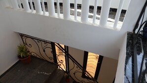Un escalier avec des rampes noires et un pot de fleurs placé sur le palier.