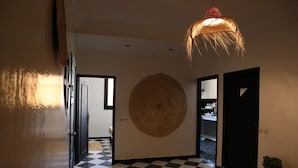 Un couloir doté d’un sol à carreaux, d’une grande décoration murale circulaire et d’un luminaire suspendu.