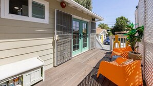 A covered outdoor area with a wooden deck, a sliding glass door, and orange outdoor furniture.
