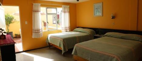 A room with two beds, a window with curtains, and a painting on the wall.