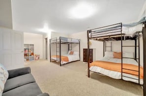 Cozy bedroom with two bunk beds, a comfortable chair, and ample storage.