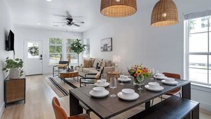 A modern dining area with a dark wooden table set for six, surrounded by chairs. There are two large woven pendant lights above the table. - Luxury Escape at The Noir: 3br, Hot Tub, & Steps From Main St! (Fredericksburg)