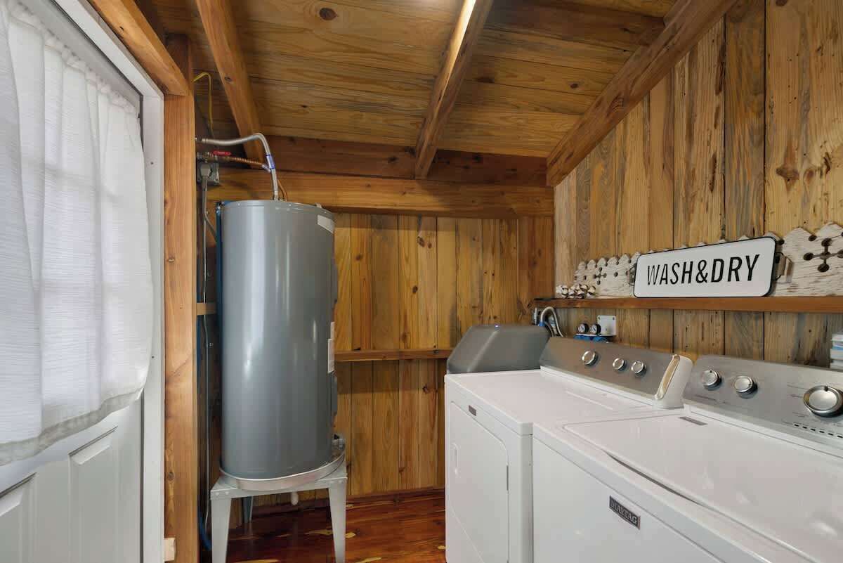 Un'area lavanderia con lavatrice, scaldabagno di grandi dimensioni e un cartello con la scritta 'WASH&DRY'.