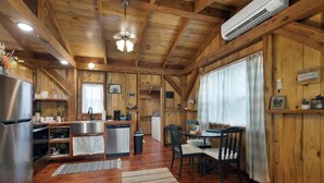 A wooden cabin interior with a kitchen, dining area, and a ceiling fan. - Saw Mill Cabin (Fredericksburg)