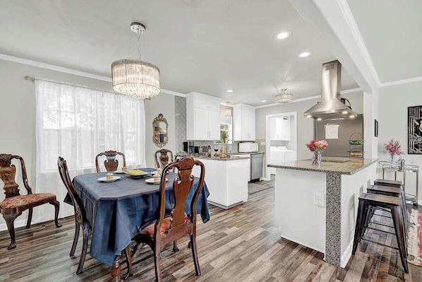 A modern kitchen with a central island, wooden dining table, and chairs.