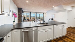 Una cocina moderna con una isla grande, electrodomésticos de acero inoxidable y una pared de acento de piedra.