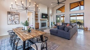 A spacious living area with a wooden dining table, a gray sofa, and a large chandelier. - Johnson City Limits Home (Johnson City)
