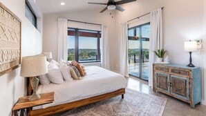A bedroom with a bed, a ceiling fan, a large window, and a view of the outdoors. - Johnson City Limits Home (Johnson City)