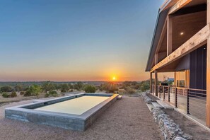 A modern house with a swimming pool and a balcony overlooking a desert landscape at sunset. - Johnson City Limits Panoramic Hill Country Views! (Johnson City)