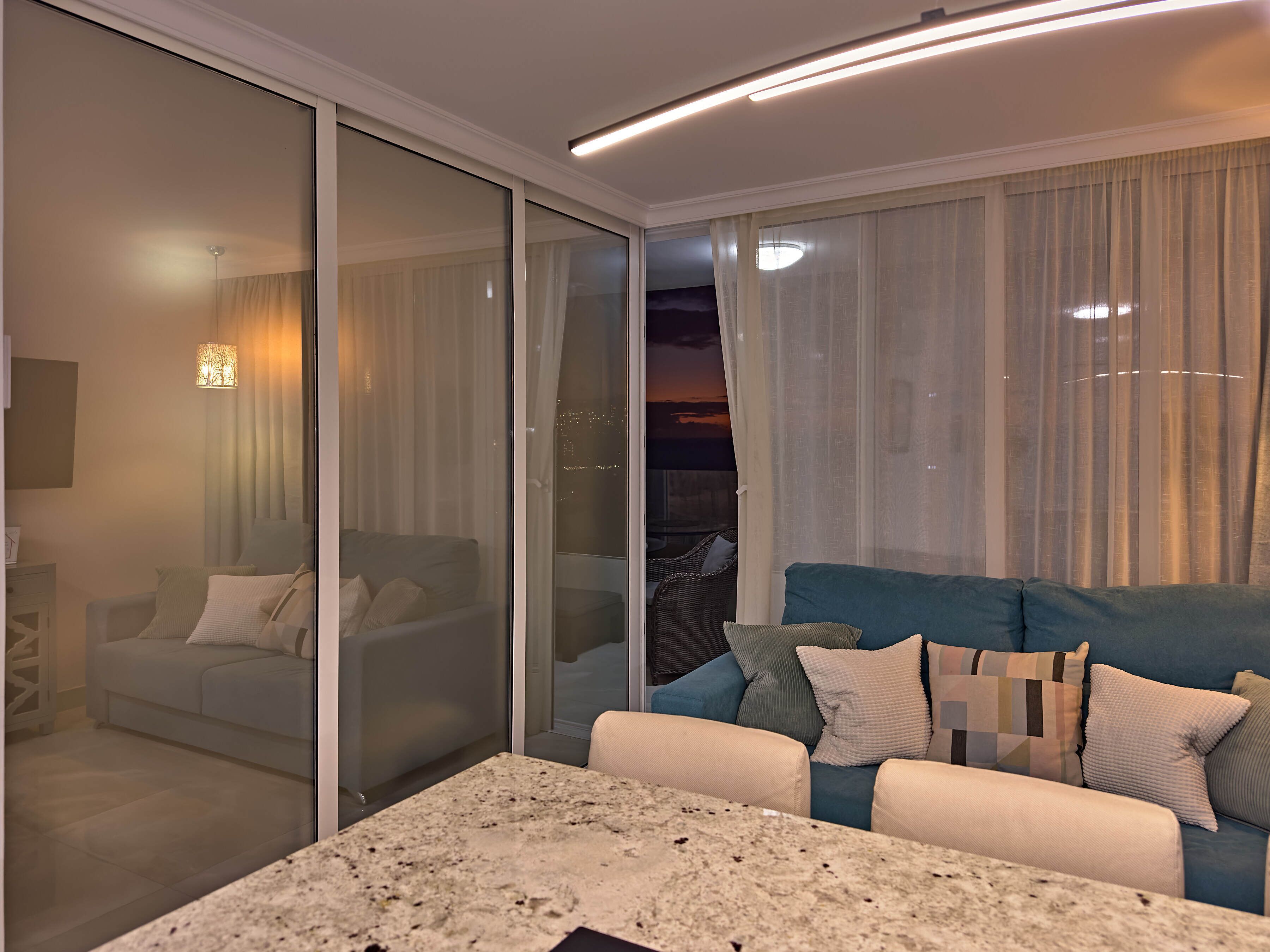 Un salon moderne avec un canapé, une table basse et une porte-fenêtre coulissante donnant sur un balcon.
