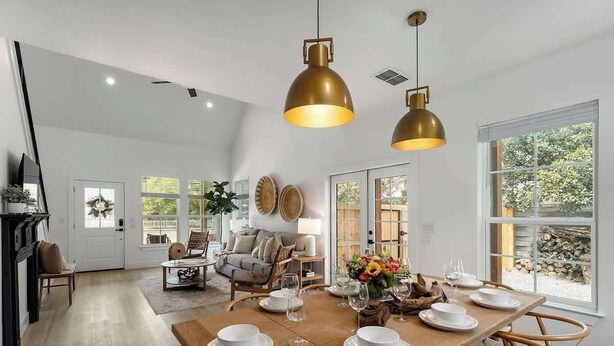 A dining area with a wooden table set for six, surrounded by wicker chairs.