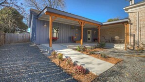 A covered patio area with a concrete pathway leading to a seating area, surrounded by gravel and small plants. - The Homestead Estate (Fredericksburg)
